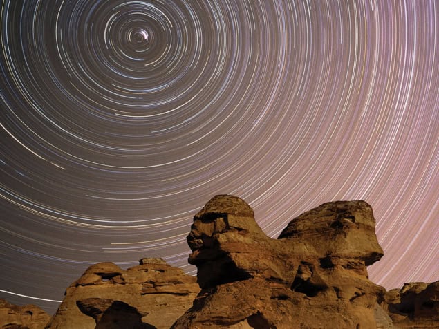 Long exposure photo of stars above desert rocks
