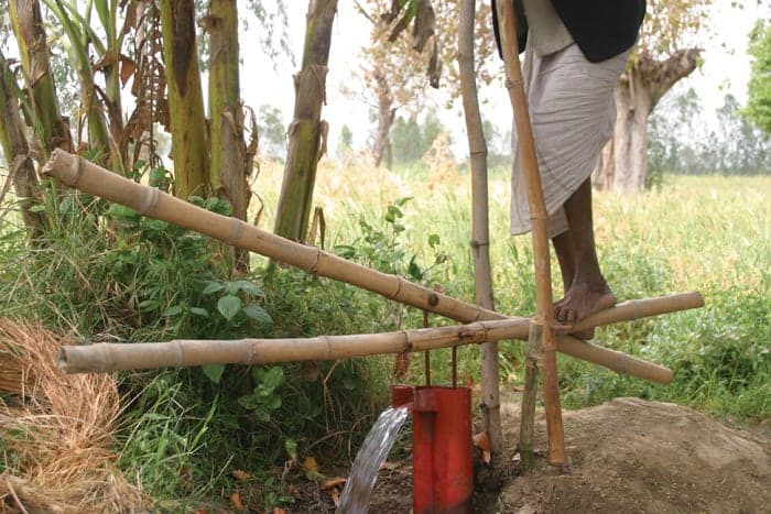 A woman works a foot-powered water pump made of bamboo &ndash; an example of appropriate technology