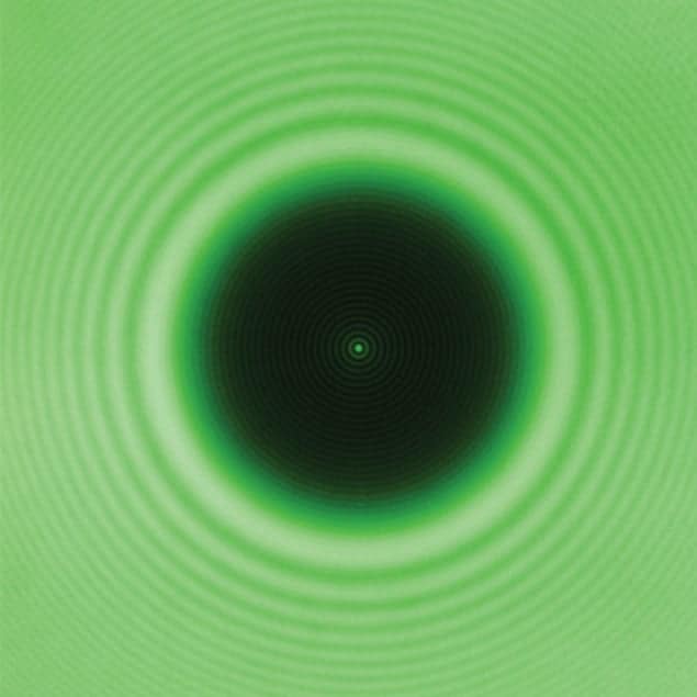 Photo of a ball bearing lit by laser light showing a tiny spot at its centre