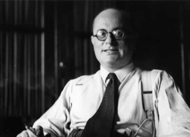 Black-and-white photo of Francis Simon, smiling and smoking a cigarette