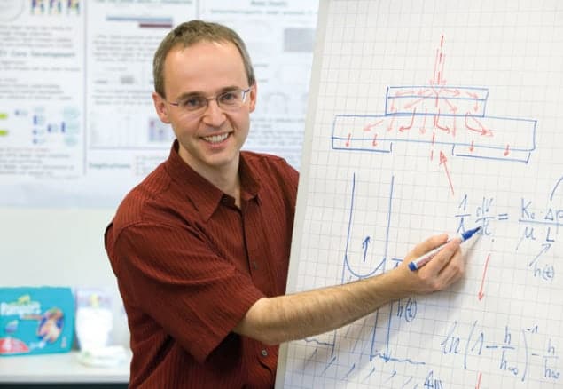 Photo of Mattias Schmidt writing equations and diagrams related to fluid flow on a grid of paper