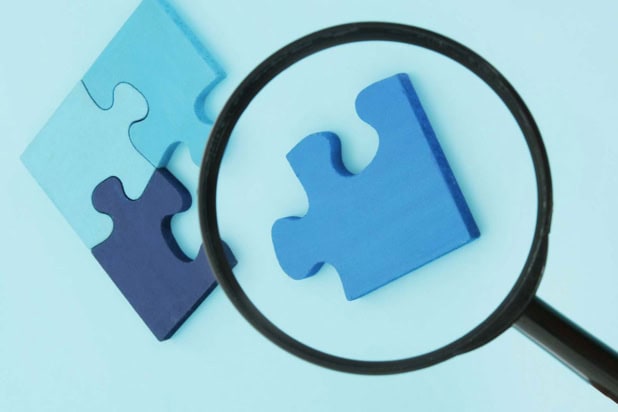 Image of jigsaw puzzle pieces under a magnifying glass