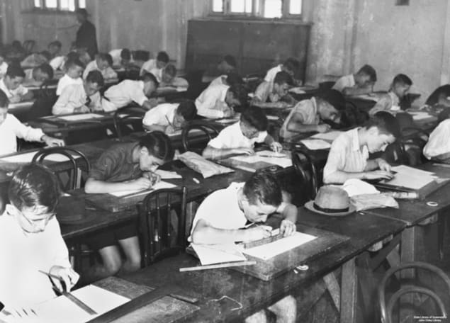 Photo of children bent over desks taking an exam