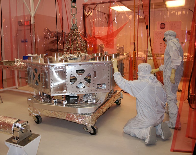 two people working on the system at Advanced LIGO for shielding it from the effects of seismic vibrations