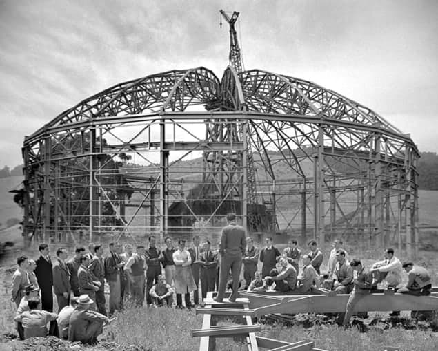 Photo showing Ernest Lawrence addressing an assembled group of workers outside the skeletal frame of the building that would house his 184-inch cyclotron