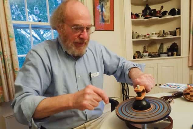 Photo of Kenneth Brecher spinning a supported top with a frame and a string