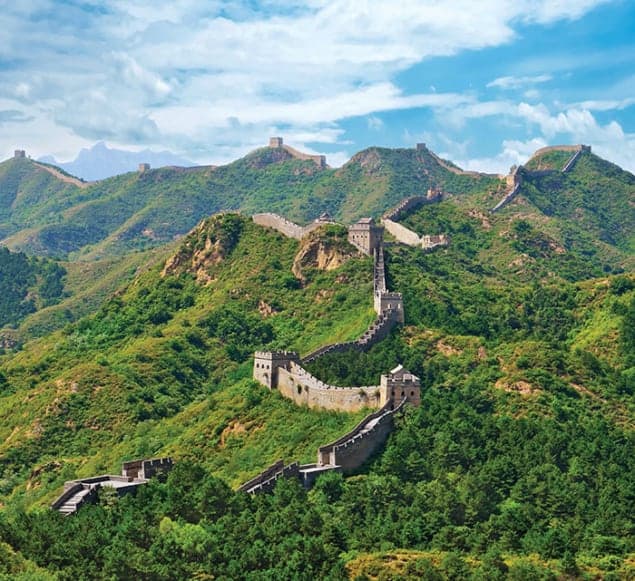 Photo of the Great Wall of China snaking over lushly forested hills