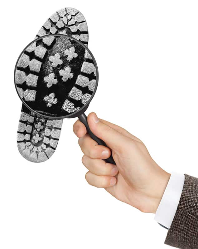 Illustration of a magnifying glass being held over the sole of a shoe with a heavy tread