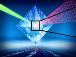 An artist's drawing of a diamond overlain with a semi-transparent pattern of 1&rsquo;s and 0&rsquo;s. A green laser-like beam enters one side of the diamond and a red beam of 1&rsquo;s and 0&rsquo;s comes out the other side. An inset drawing shows a ball-and-stick model of atoms that make up the structure of diamond with NV defects. Black carbon atoms in a lattice surround a single blue nitrogen atom