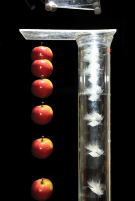 Series of superimposed photographs showing the free fall of an apple next to the free fall of a feather in a vacuum chamber. Both apple and feather fall at the same rate