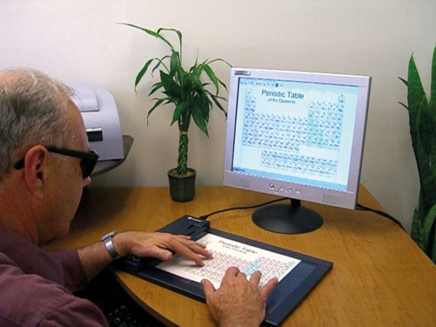 Photograph of John Gardner using audio-tactile technology to explore the periodic table