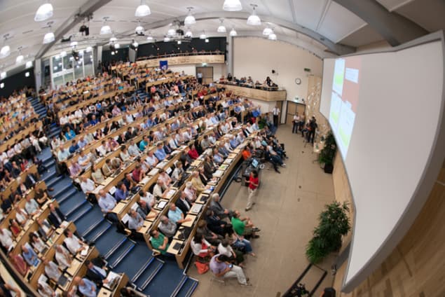 Physicists in CERN's main auditorium listen as the latest data from the Large Hadron Collider are presented