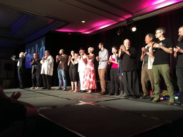 Photo of G4G13 banquet performers. Emcee and magician Mark Mitton is at the far left, followed by James Gardner, Martin’s son. Acrobat Roxana is fifth from left (in black), and Rubik’s cube speed-solver Sydney Weaver ninth from left