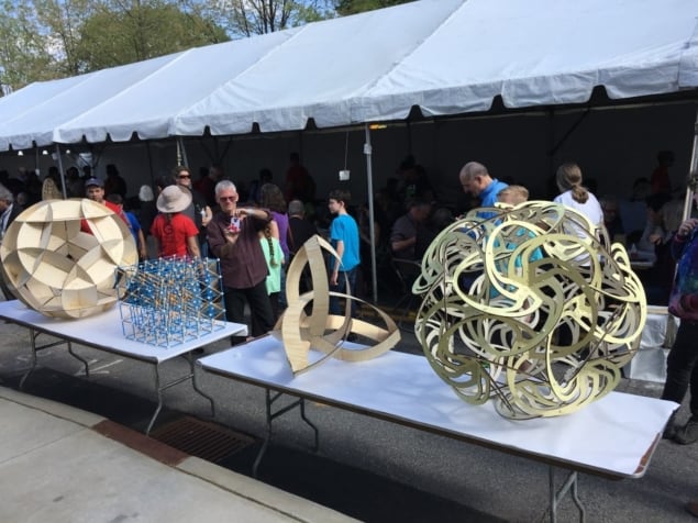 Photo of some of the mathematical constructions at G4G13. Bjarne Jesperson’s “Knotted Cube” is second from right.