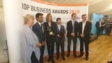 A group of people standing with an award in front of a sign reading "IOP Business Awards 2018"