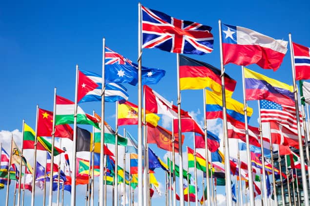 A photo of many countries' flags, flying on flagpoles