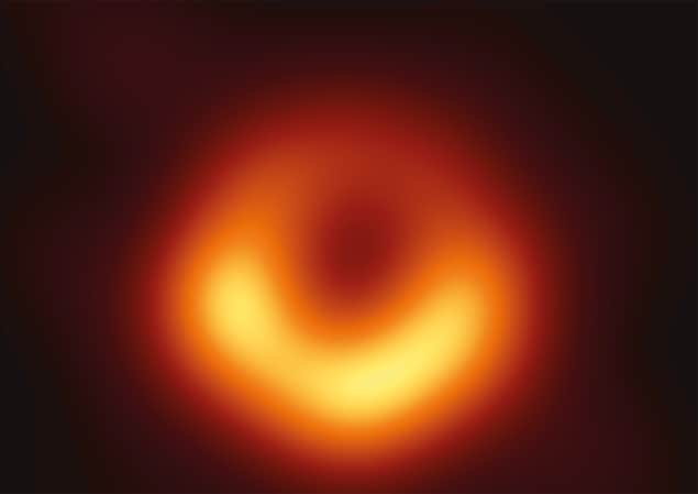 Image of the M87 Black Hole - a yellow ring thicker at the bottom surrounding a dark circle.