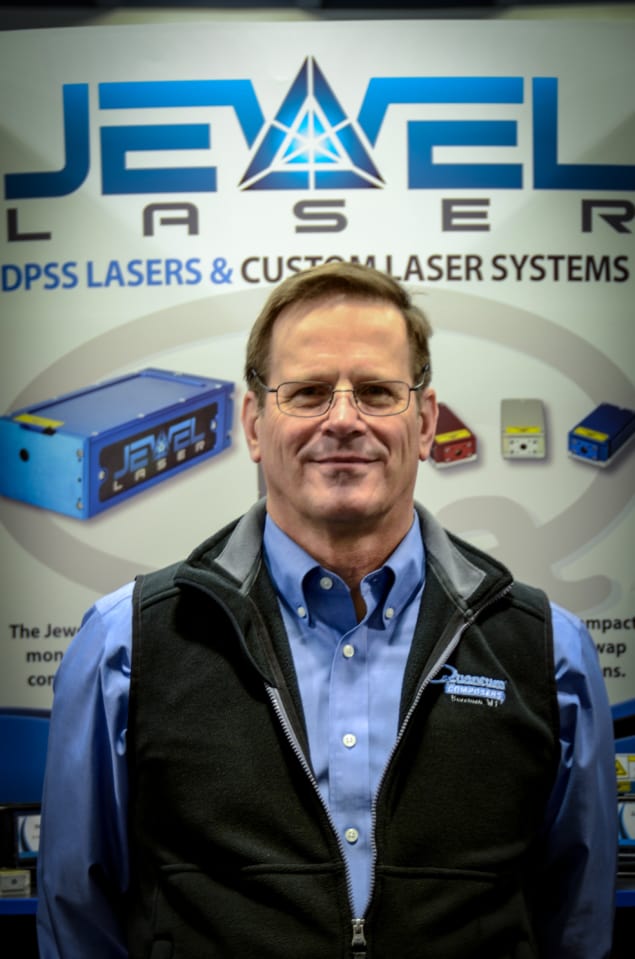 Photo of Steve Birrell standing in front of an advertisement for Jewel Lasers