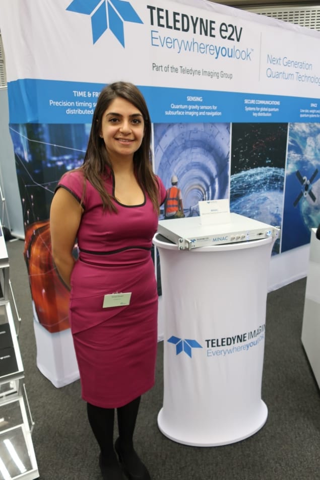 A woman standing next to a podium with an oblong box (the atomic clock) on top of it