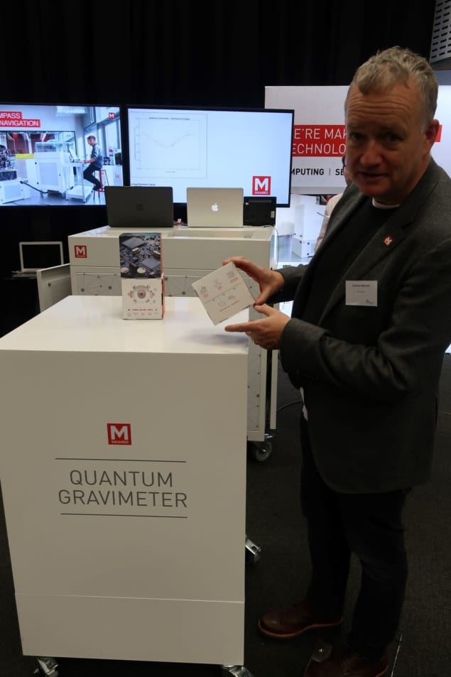 A man standing next to a large white box labelled "quantum gravimeter"