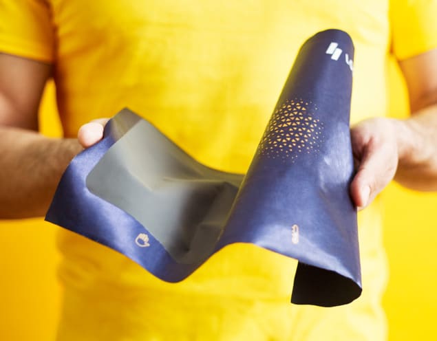A man holding the LOOMIA electronic layer, which is a piece of flexible blue fabric containing electronic circuitry