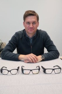 A man sitting at a table with three pairs of glasses in front of him