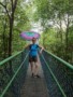 Ana Rakonjac standing on a bridge between trees holding an umbrella