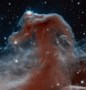 A photo of the Horsehead Nebula showing reddish gas in front of a starry background