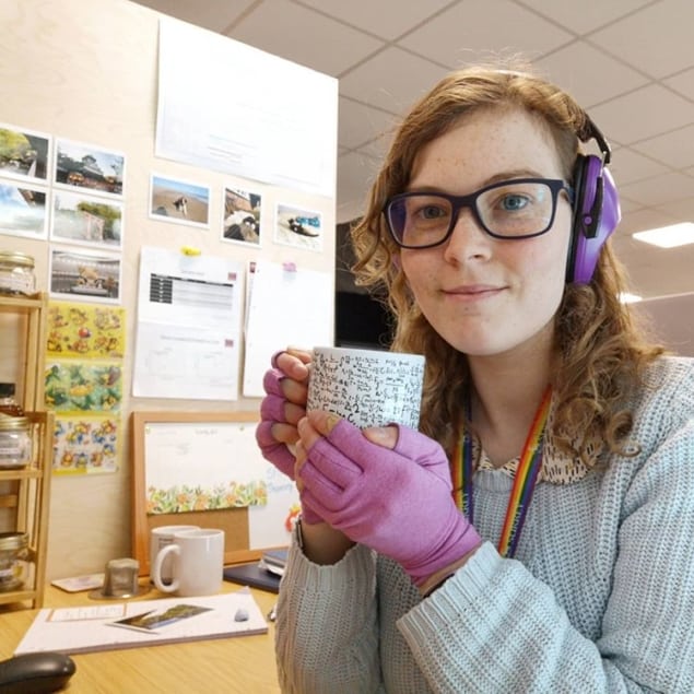 Daisy Shearer wearing gloves and ear defenders in an office