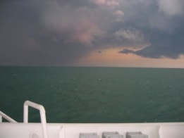 Thunder clouds gather over the ocean as seen from the deck of a ship