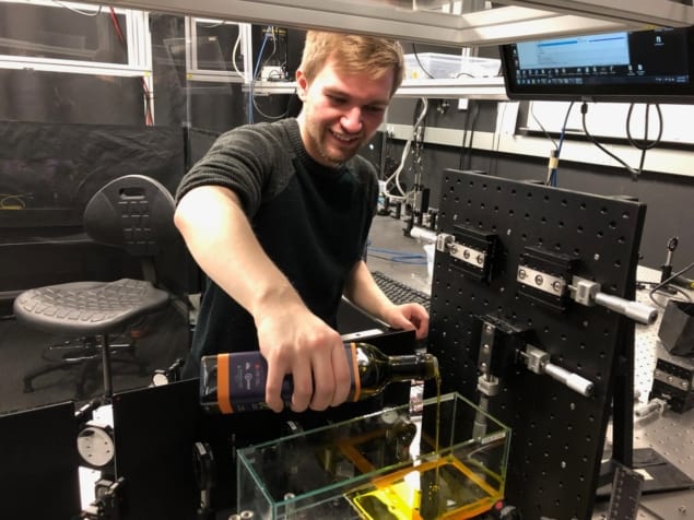 Michael DelMastro pours oil into the optical chamber