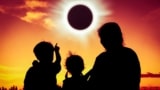 Silhouette back view of family sitting and watching a solar eclipse