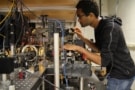 Photo of Garrett Williams, adjusting equipment on an optical bench