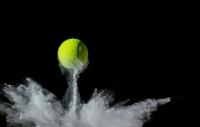 a tennis ball bouncing, throwing up chalk dust