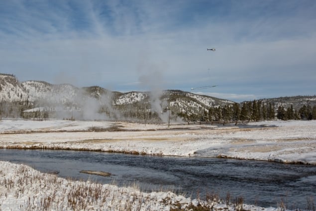 A helicopter flying through the steam above Old Faithful geyser
