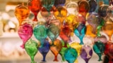 Dozens of colourful glass baubles suspended in a shop window