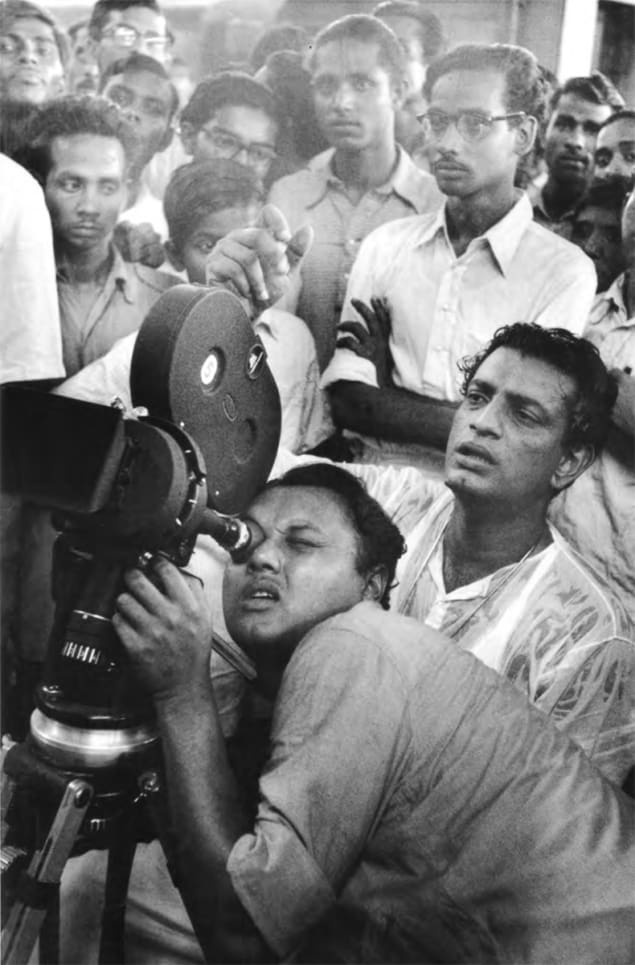 Satyajit Ray, sitting behind the camera operator, on set