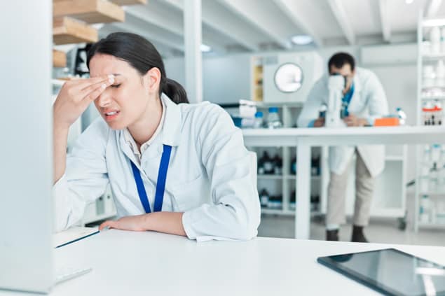 Woman sat at a desk with her head in her heads