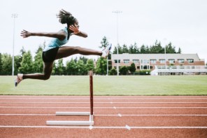 Hurdler mid-jump on an athletic track