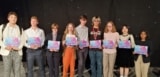 Photo of a line of young people holding prize certificates