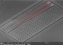 Image of the erbium device, which is a grey chip containing a grid of holes and two ribbon-like channels