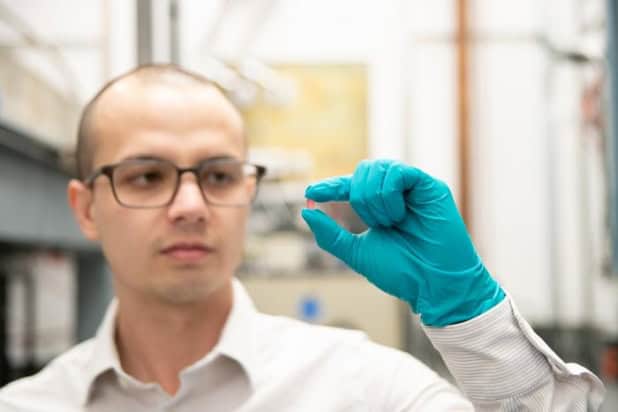 Christopher Simon holds a crystal of lithium holmium yttrium fluoride in his gloved hand