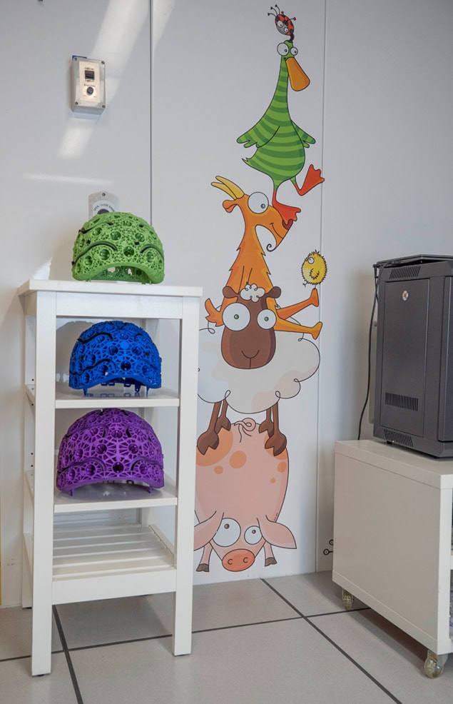 Three complex-looking helmets on shelves next to a fun child-friendly mural