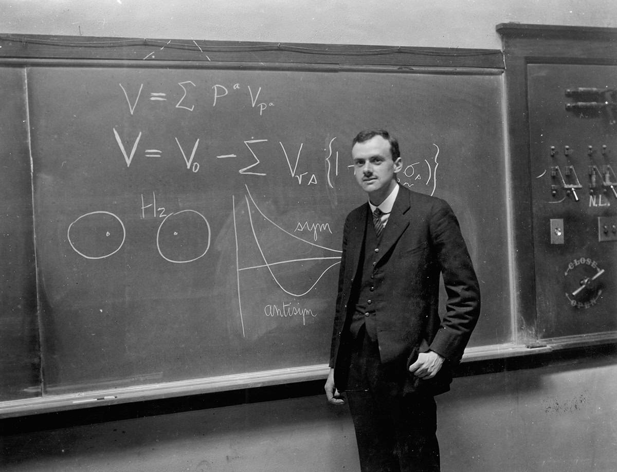 Paul Dirac next to a blackboard