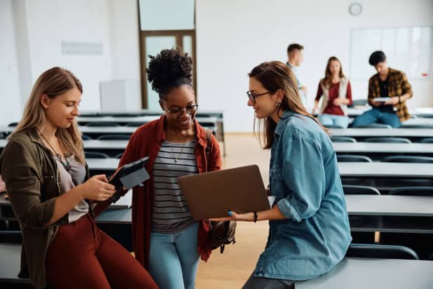 Multiracial group of female students using wireless technology in university classroom