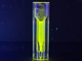 A small vial containing fluorescent yellow supraparticles