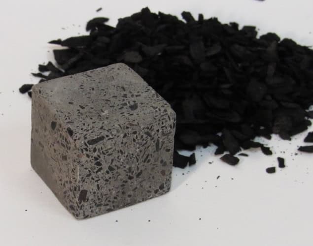 Photo of biochar, a black powder, next to a piece of concrete with biochar as a cement filler. The concrete contains black flecks among the aggregate.