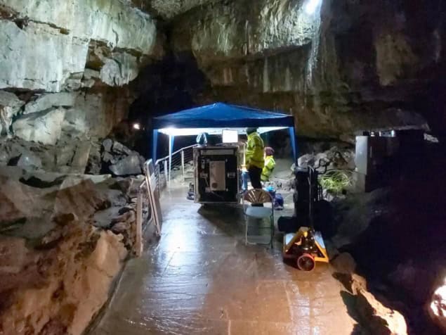 Two people in hi-vis with a large metal object in an underground cavern Two people in hi-vis with a large metal object in an underground cavern