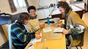 Three adults at a table with craft supplies