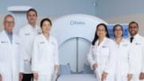 Clinicians in white coats stood around a large medical scanner labelled Elekta